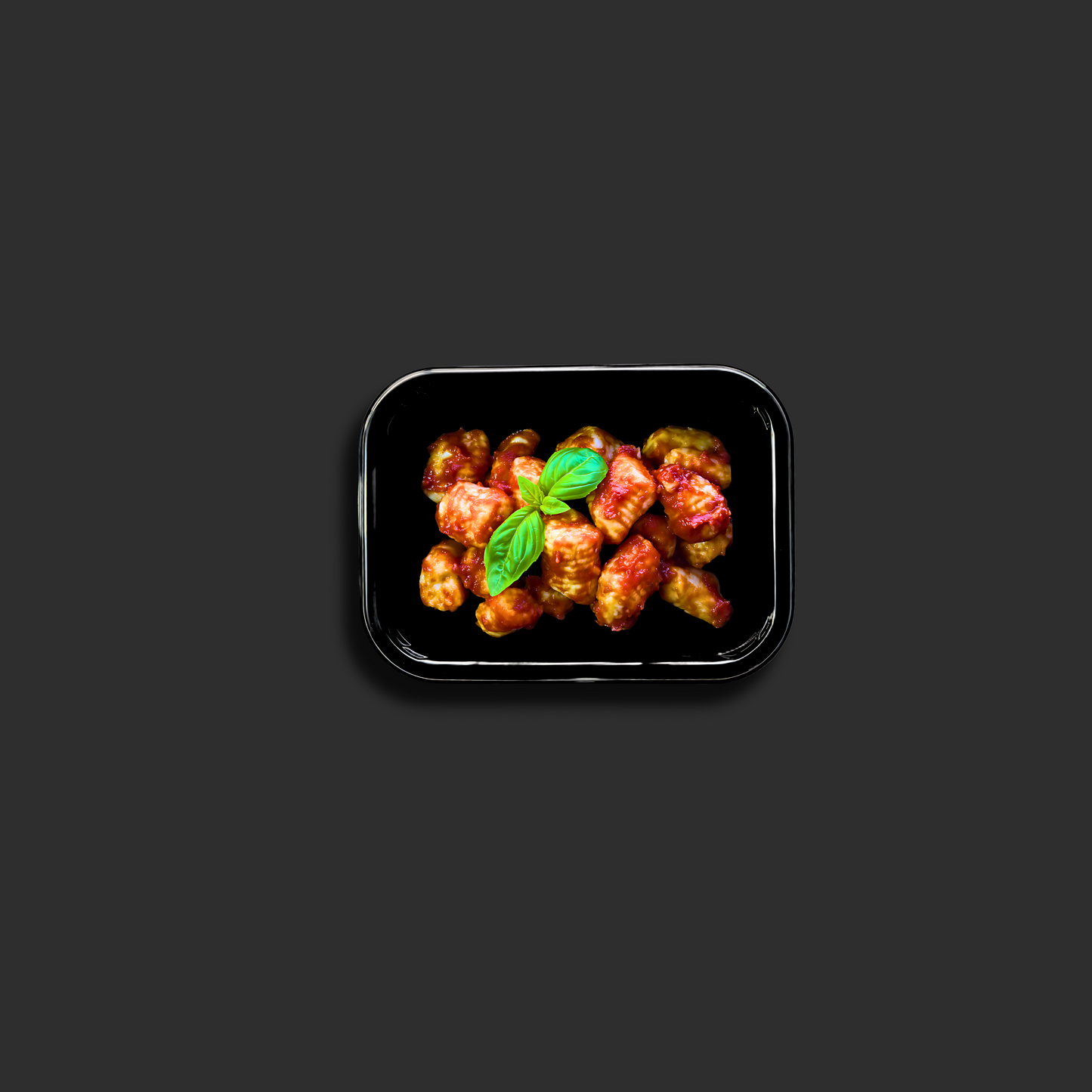 Gnocchi Napolitana served in a black ready meal container with potato dumplings in tomato sauce and basil garnish