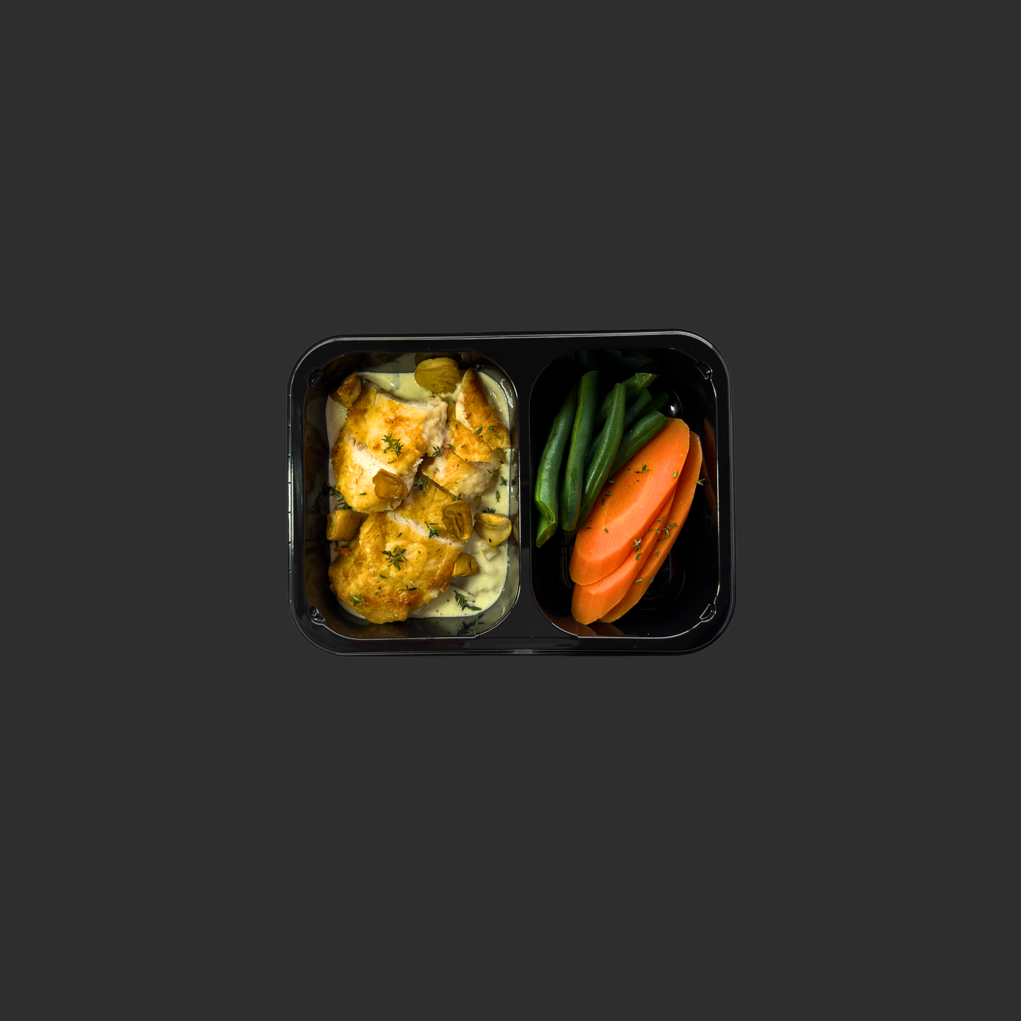 Chicken tenderloin with creamy mushroom sauce in one compartment of a black ready meal container, with steamed carrots and beans in a separate compartment