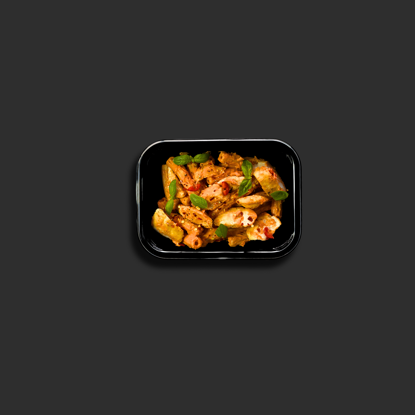 Chicken Vodka Rigatoni served in a black ready meal container with chicken, pasta, creamy tomato vodka sauce, basil and chili flakes