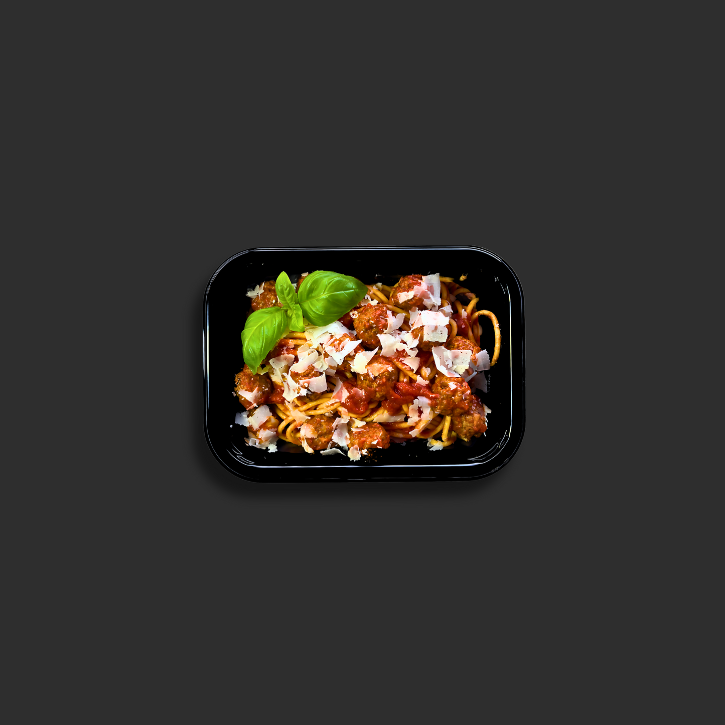 Spaghetti and meatballs with Napolitana sauce in a black ready meal container with basil garnish