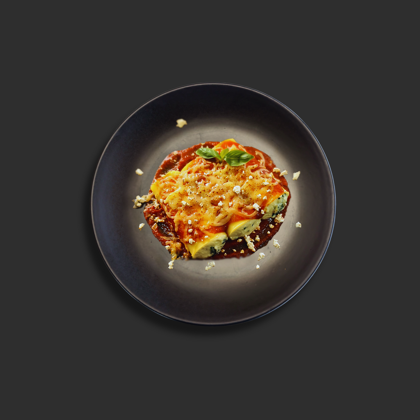 Xchef Gourmet Spinach and ricotta cannelloni with melted mozzarella and Napolitana sauce, garnished with basil on a black plate