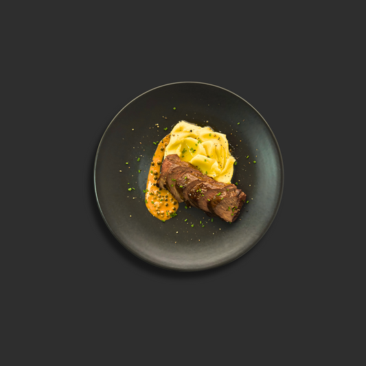 Premium Australian grass-fed beef tenderloin with rich creamy green peppercorn sauce, served with buttery mashed potato on a black plate
