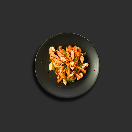 Chicken Vodka Rigatoni with tender chicken and rigatoni pasta in creamy tomato vodka sauce, garnished with fresh basil and chili flakes on a black plate.