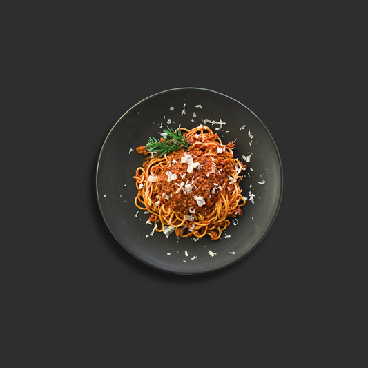 Spaghetti Bolognese with rich meat sauce, featuring al dente spaghetti pasta topped with traditional Italian beef and tomato Bolognese sauce and grated parmesan cheese on a black plate.
