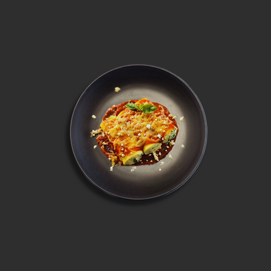 Xchef Active Spinach and ricotta cannelloni with melted mozzarella and Napolitana sauce, garnished with basil on a black plate