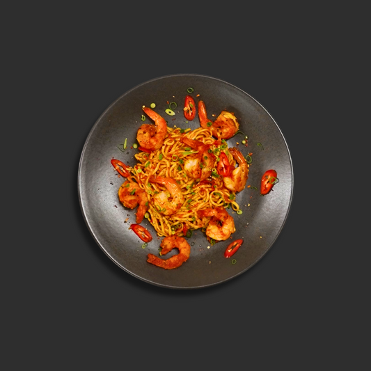 Linguine Prawn Arrabbiata with fresh garlic prawns and linguine pasta in chili infused tomato sauce, garnished with chili on a black plate
